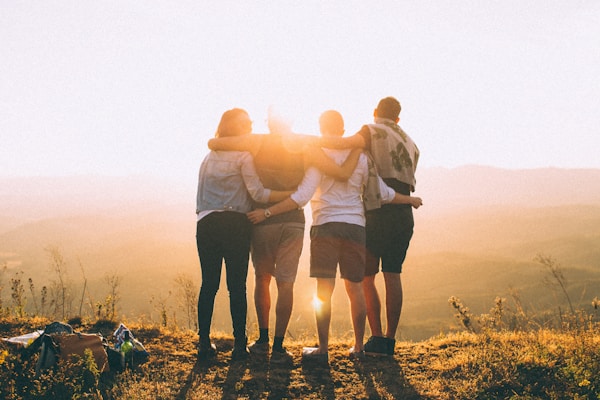 Friends with arms around each other watching the sunset